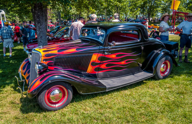 1934 Ford 3 window coupe hot rod Moncton, New Brunswick, Canada - July 11, 2009. Centennial Park. A beautiful, traditional styled hot rod is on display in Centennial Park during the 2009 Atlantic Nationals Automotive Extravaganza. People walk among the classic cars looking  at the cars and chatting with other automotive enthusiasts. 1934 stock pictures, royalty-free photos & images