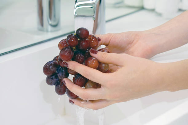 istock Girl washes the grapes under the tap 1065908214