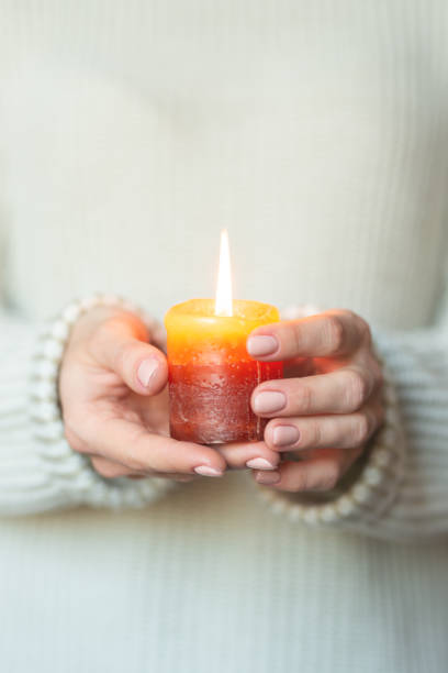 istock A woman in a light warm woolen keeps a burning candle in her hands, copy space, selective focus. Christmas, new year holiday concept 1065917124