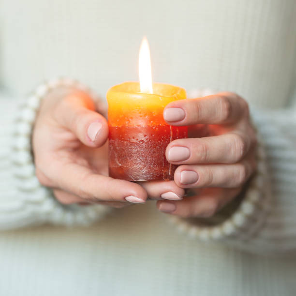 istock A woman in a light warm woolen keeps a burning candle in her hands, copy space, selective focus. Christmas, new year holiday concept 1065919762