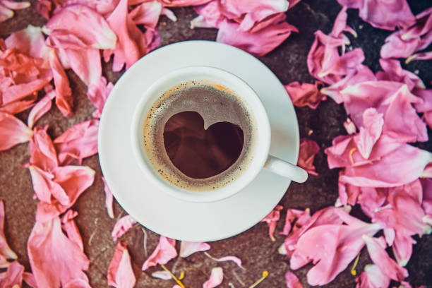 flache laien tasse kaffee mit herz form muster mit leichten rosa pfingstrose blüten auf schwarzem stein umgeben. valentinstag, guten morgen-konzept. ansicht von oben, nahaufnahme. - comfort food high angle view directly above close up stock-fotos und bilder