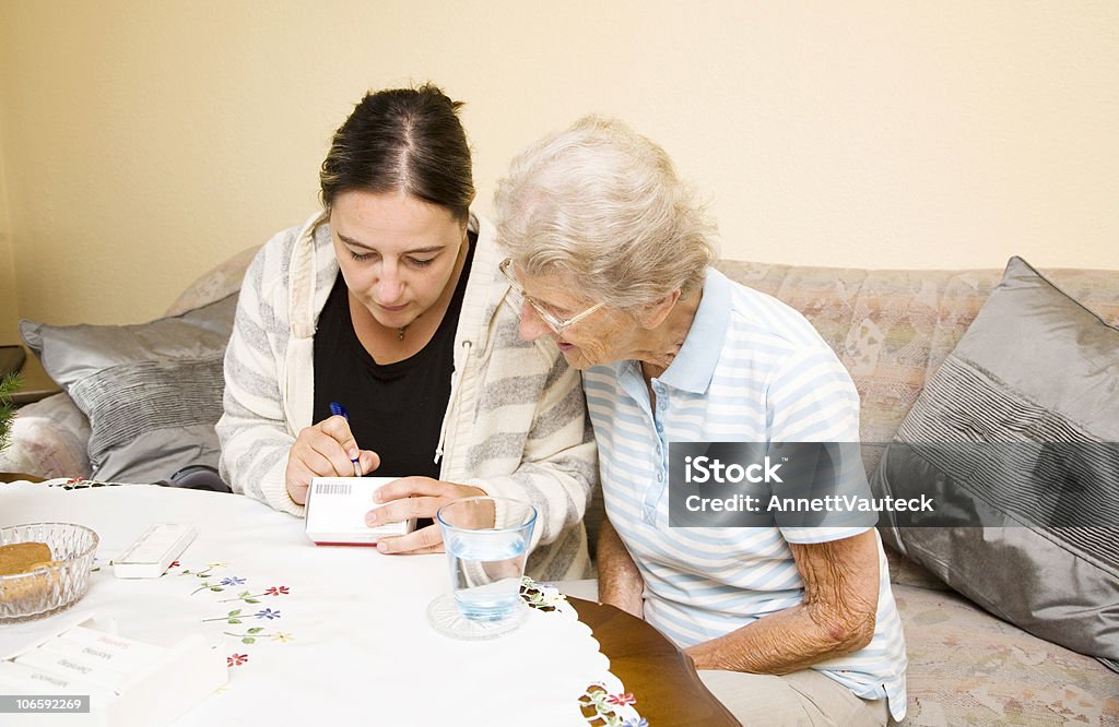 home visit nurse visiting a senior woman at home and showing her the new pills,more seniors here: 30-39 Years Stock Photo