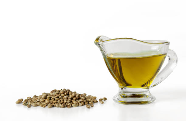 a heap of hemp seeds and hemp-seed oil in a glass gravy boat. isolated on white background - hemp seed heap white imagens e fotografias de stock