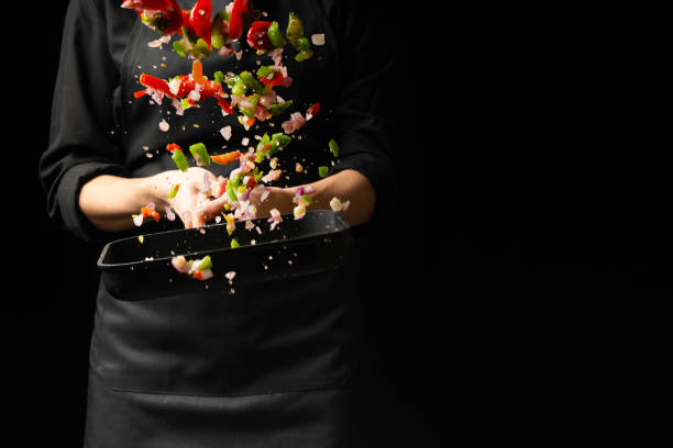 istock The chef prepares the vegetables on the pan. Black background for copying text. Restaurant business and advertising. 1065950362