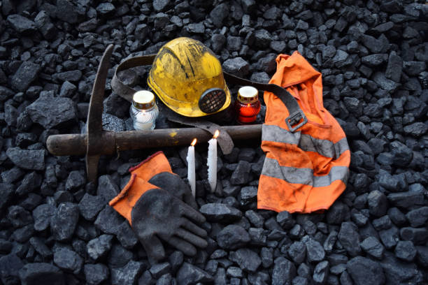 istock Vigil light, candle with the miner belongings (helmet, gloves, pickaxe, vest, belt) 1065950532