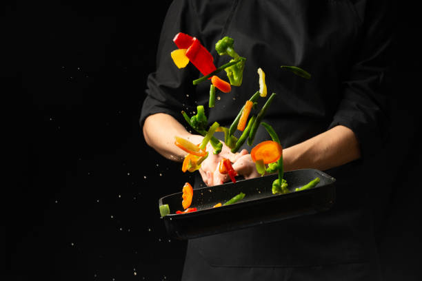 istock Professional cook. He prepares a dish with vegetables in a saucepan. on black background, menu, recipe book, healthy food 1065952636