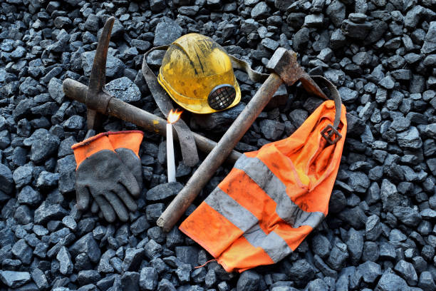 istock Vigil light, candle with the miner belongings (helmet, gloves, pickaxe, vest, belt) 1065953922