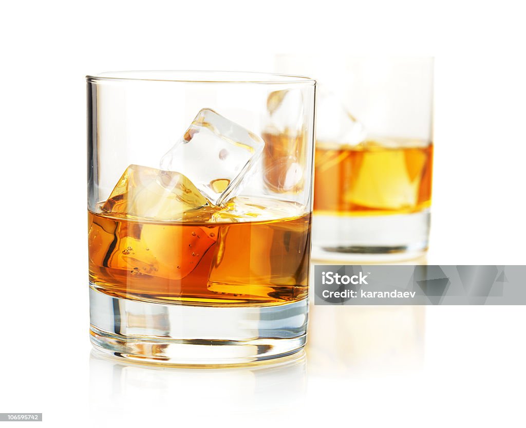 Two half-filled hgh ball glasses of whiskey with ice Two whiskey glasses. Isolated on white with reflection Alcohol - Drink Stock Photo