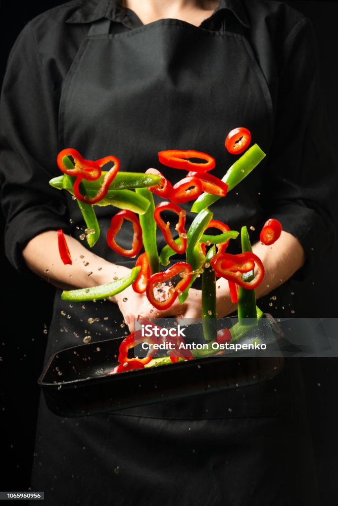 Cooking fresh vegetables in the pan chef. Vertical viewing of photos. Dark black background Chef Stock Photo