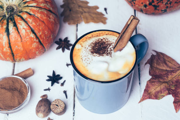 istock Pumpkin spice latte or coffee with cinnamon and nutmeg. Autumn, fall or winter hot drink. Old white wooden background with yellow leaves and pumpkins 1065978906