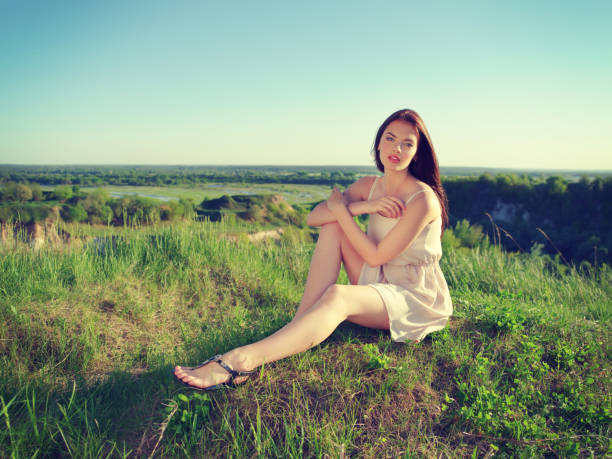 istock Young woman sitting by a cliff outdoors on nature 1065984892