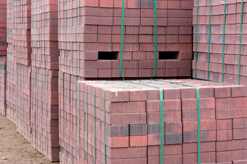 Close-up of clay four holes red bricks stacked together on a construction site.