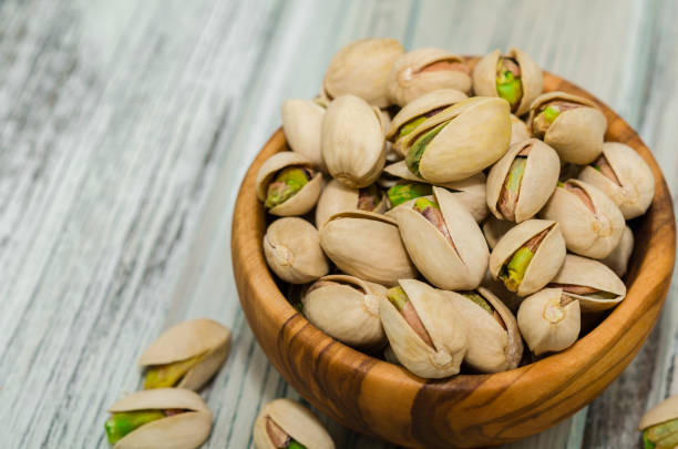 istock Pistachios with shell in a bowl on rustic wooden surface. Pistachios. 1065991012