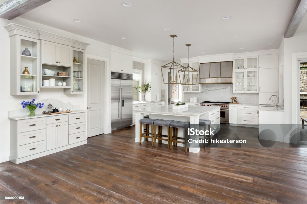 beautiful kitchen in new luxury home with island, pendant lights, and hardwood floors kitchen in newly constructed luxury home Flooring Stock Photo