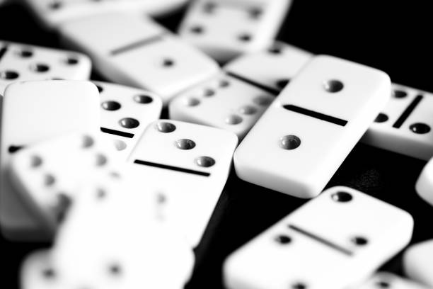 istock Dominoes are scattered on a dark surface close up. Black and white 1066056496