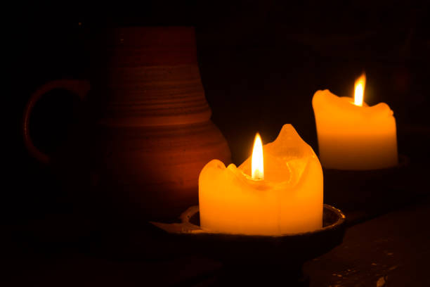 istock Two burning candles in the dark. clay mug on the table. glowing flame 1066065192