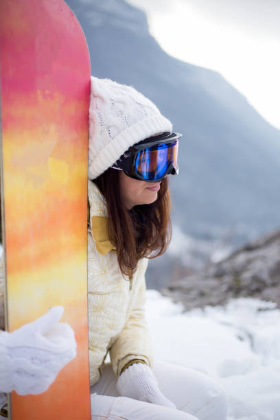 istock Woman holding snowboard with mountains in background 1066065606