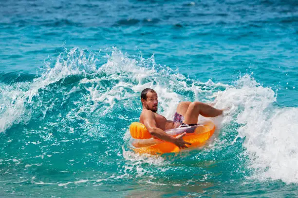 Photo of Funny man riding on tubing in breaking sea waves