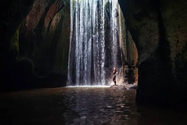 Photo of Woman stand under cave waterfall