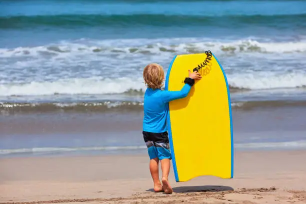Photo of Little surfer run with bodyboard on sea beach