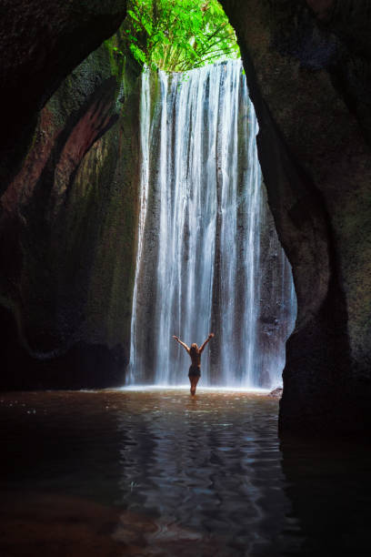 istock Woman stand under cave waterfall 1066069974
