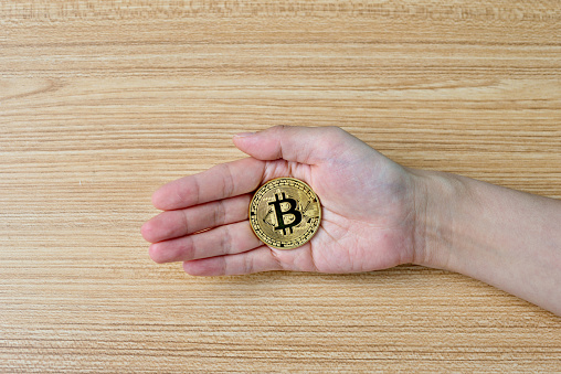 Fujian, China - May 30, 2018: Human hand holding bitcoin coin. Bitcoin is virtual currency.