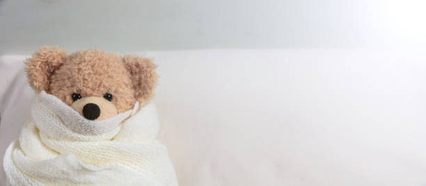 simpatico orsacchiotto coperto da una coperta calda, sdraiato a letto - baby sleeping bedding teddy bear foto e immagini stock