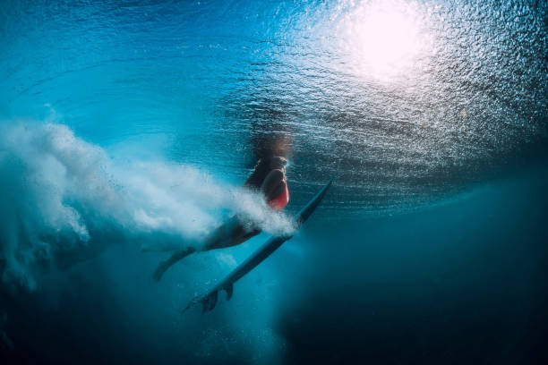 istock Surf girl with surfboard dive underwater with under big wave. 1066088332