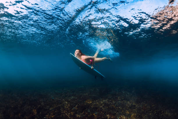 istock Sporty surfer woman dive underwater with under wave. 1066088372