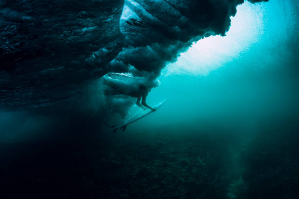 istock Surfer with surfboard dive underwater with under big wave. 1066088428