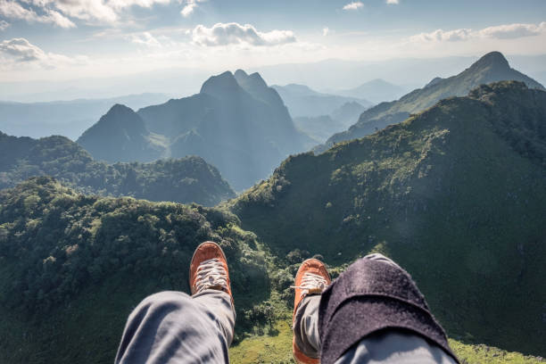 istock Legs traveler relaxing and hanging on cliff with evergreen mountain 1066088892