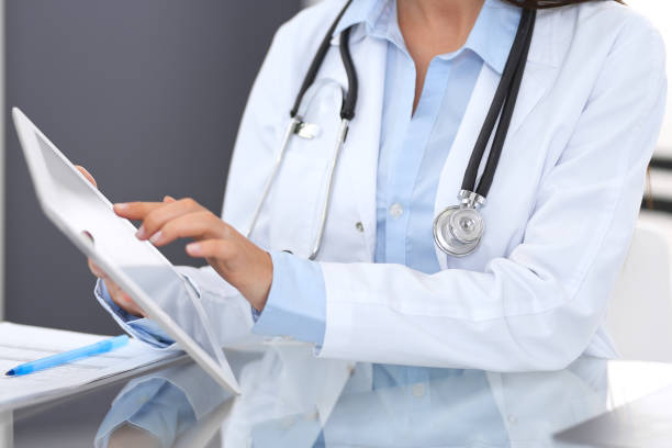 istock Close-up of female physician hands using digital tablet  while sitting at glass desk at hospital office. Medicine and healthcare concept 1066089010