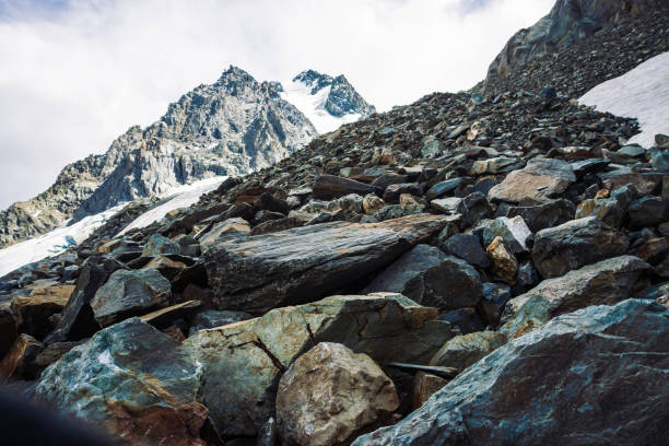 Snow on mountain range. Atmospheric snowy ridge under cloudy sky. Wonderful giant rocks in overcast weather. Climb high in mountains. Amazing minimalistic landscape of majestic nature of highlands.
