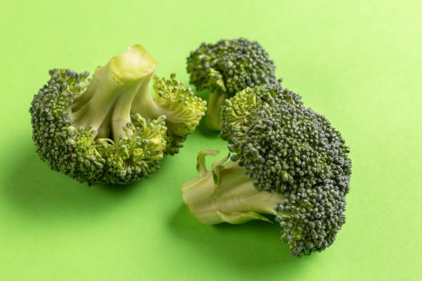 istock Fresh raw pieces of broccoli on bright green background. Copy space 1066104022