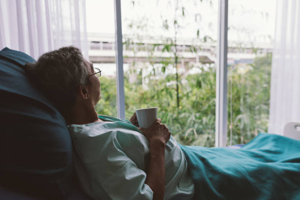 部屋で一人で病院のベッドに年配の男性 - lying in wait ストックフォトと画像