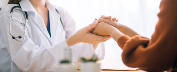 Doctor woman holding hand for reassuring her female patient. stock photo