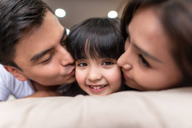 Asian Parents kissing their little daughter on both cheeks. Asian Parents kissing their little daughter on both cheeks. happy malay couple stock pictures, royalty-free photos & images