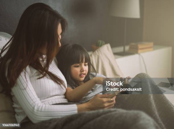 Mother And Daughter Reading Book At Home In The Bedroom Stock Photo - Download Image Now