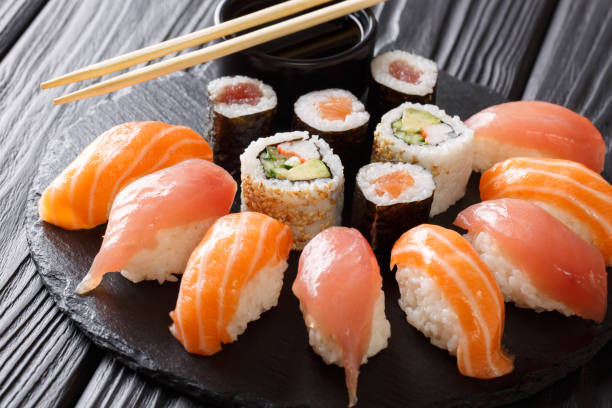 istock Sushi rolls set served on black stone slate on dark background 1066110160