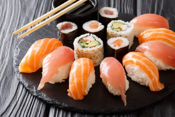 Photo of set of sushi and rolls with salmon and tuna, avocado, california, maki, soy sauce, chopsticks close-up. horizontal