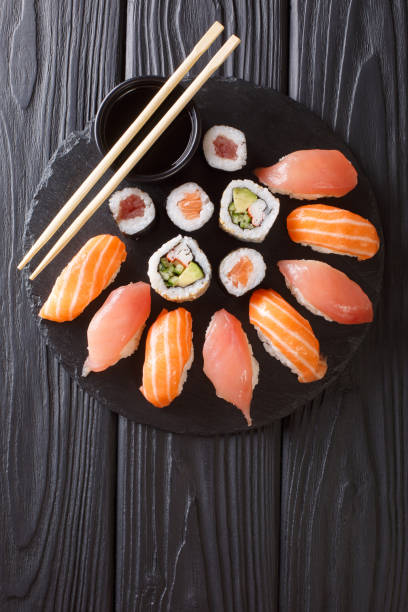 istock Sushi rolls set served on black stone slate on dark background. Vertical top view 1066110312