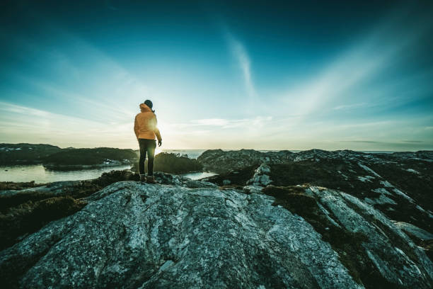 man mountain hiking by a fjord in norway - climbing men sea cliff imagens e fotografias de stock