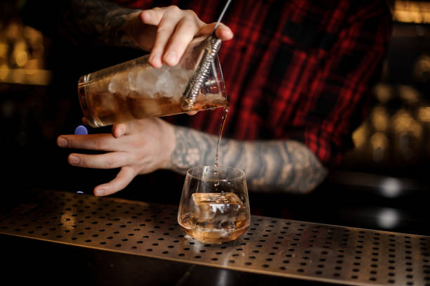 istock Bartender pouring fresh drink into a whiskey dof glass 1066135600