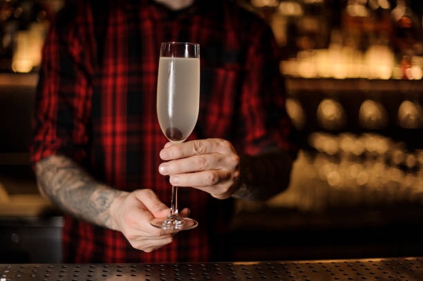 istock Bartender with tattoos holding a French 75 cocktail 1066135698