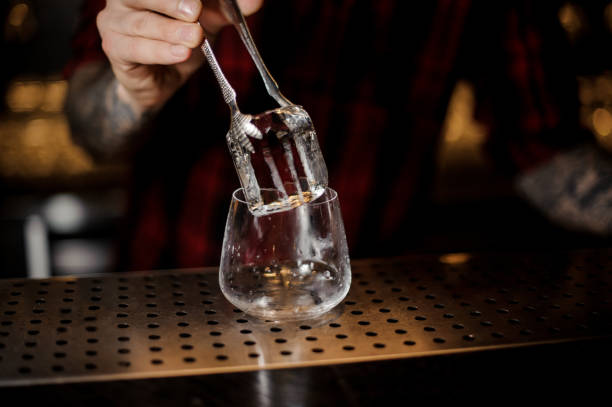 istock Barman hand putting a big ice cube into a whiskey dof 1066135770