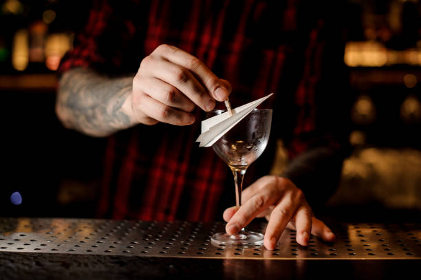 barman decorating cocktail glass with a paper plane - men elegance cocktail cool imagens e fotografias de stock