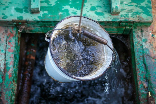 Clean and clear rainwater in a bucket is raised from a well stock photo