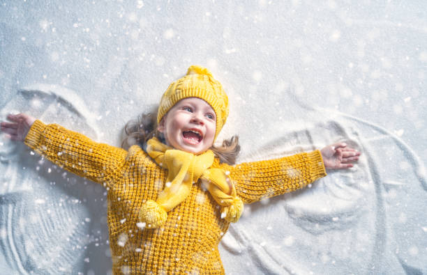 Kid making snow angel. Happy child girl playing on a winter walk in nature. Kid making snow angel. children in winter stock pictures, royalty-free photos & images