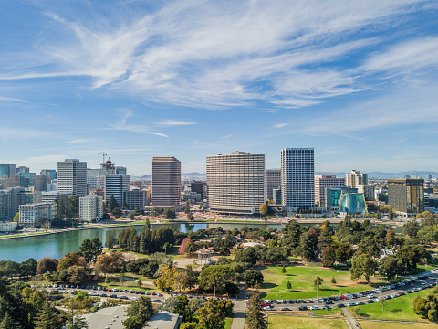 Aerial view of Lake Merritt and downtown Oakland on a sunny day. Skyscrapers fill the horizon with a bright blue sky. Downtown district fills the waterfront.