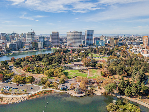 Aerial view of Lake Merritt and downtown Oakland on a sunny day. Skyscrapers fill the horizon with a bright blue sky. Downtown district fills the waterfront.